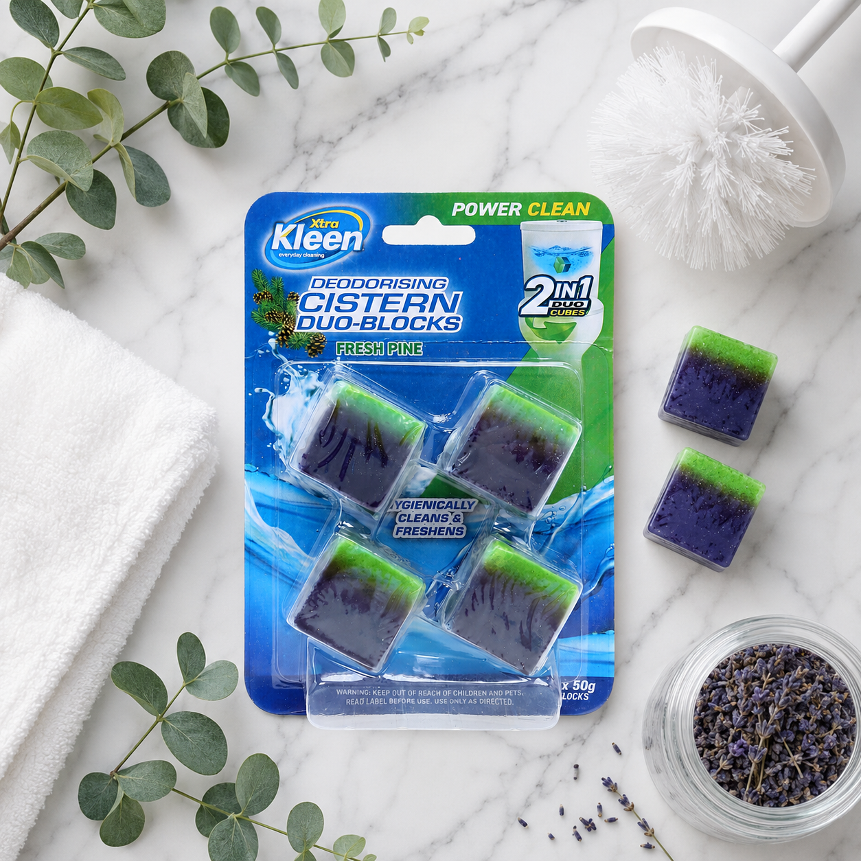 Flat lay of Xtra Kleen Cistern Duo-Cubes with botanical eucalyptus leaves and lavender accents on a light surface